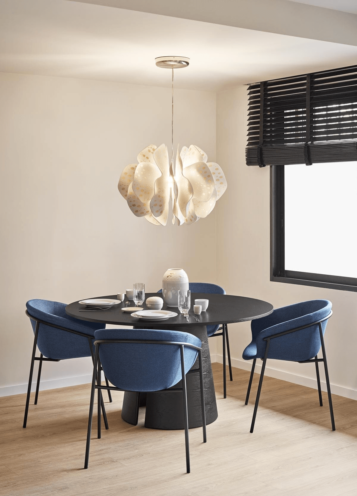 Lladró - Nightbloom Pendant Light - N60 - Golden Luster illuminating a dining area with blue chairs and a black table.
