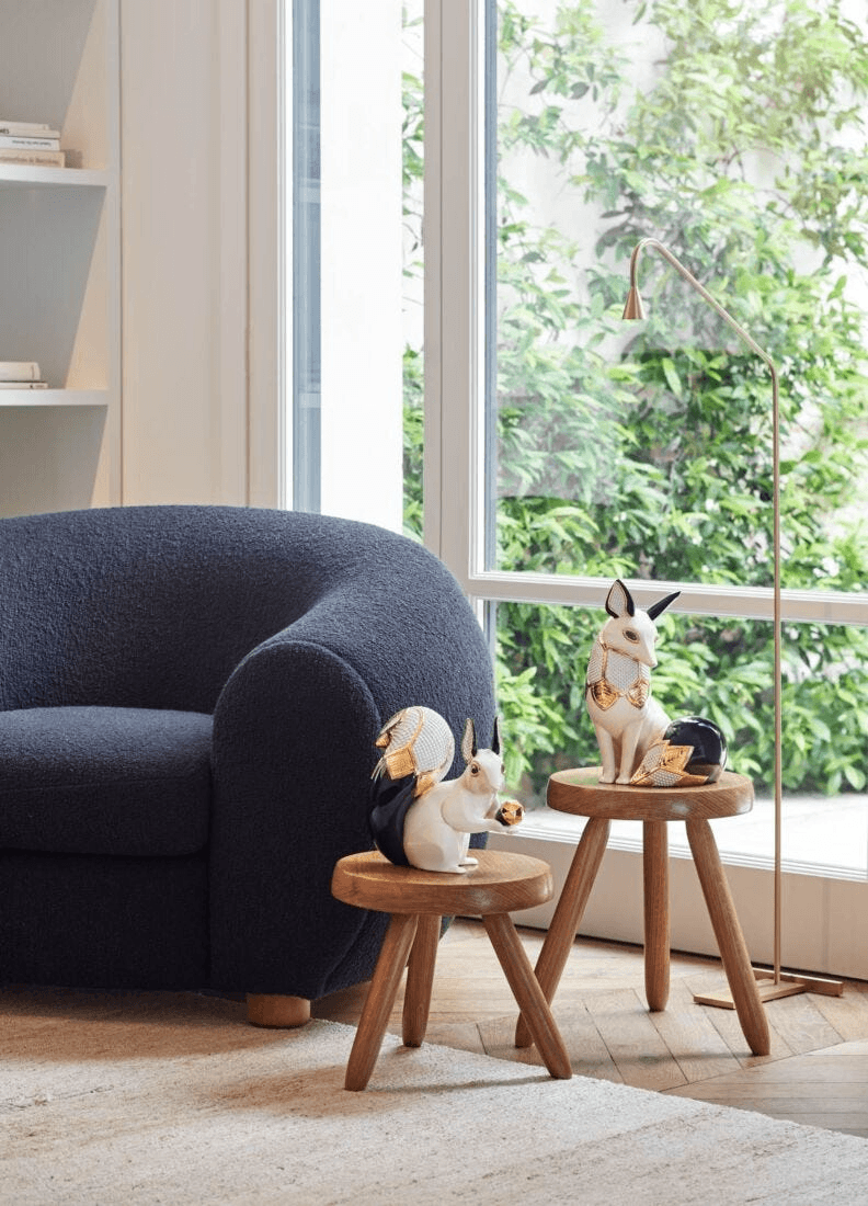 Lladró - Squirrel Jewel Sculpture displayed on wooden stools in a modern living room setting.