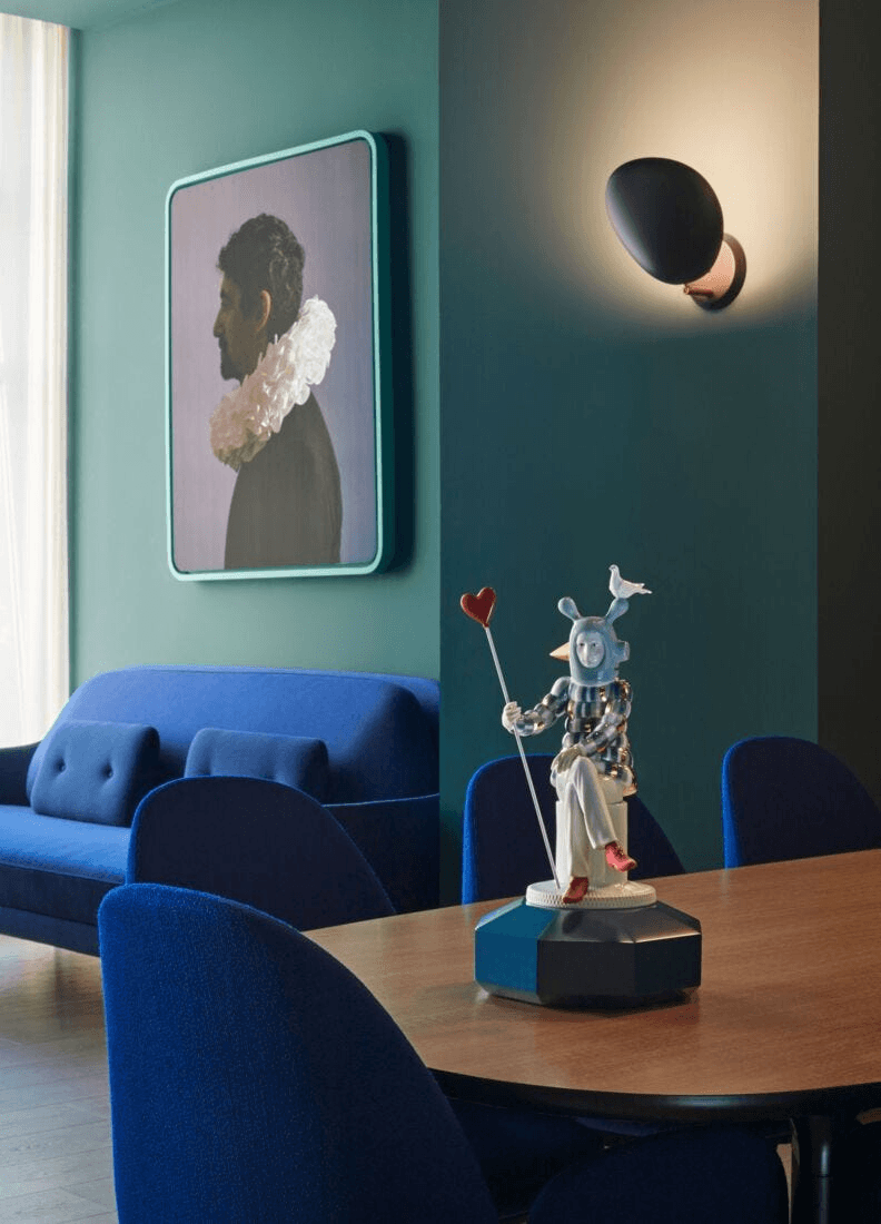 Lladró - The Lover III Sculpture displayed on a table with blue furniture in a stylish interior setting.