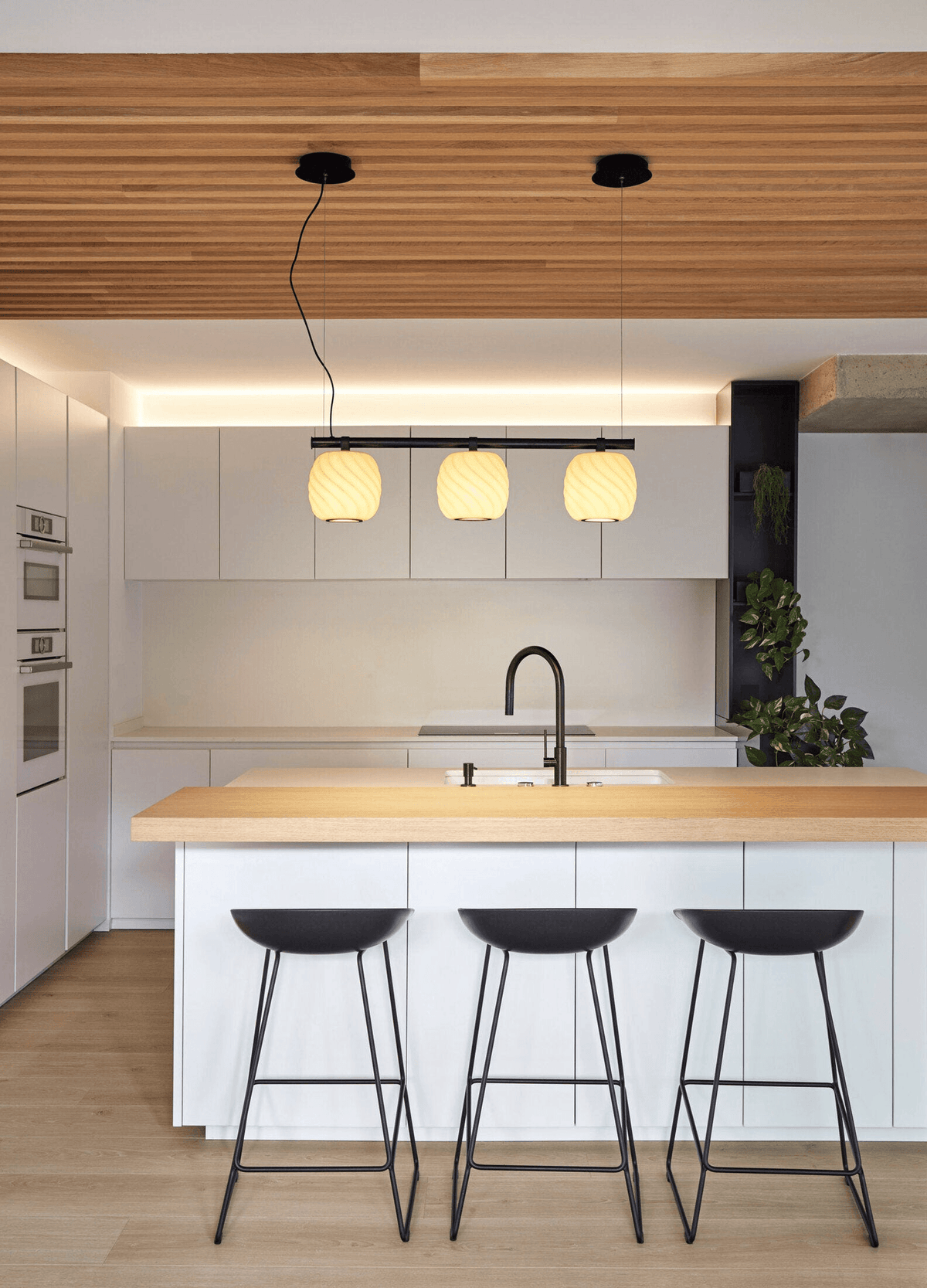 Lladró - Ice Cream Pendant Light 3 Lights above modern kitchen island with black stools and wood countertop.