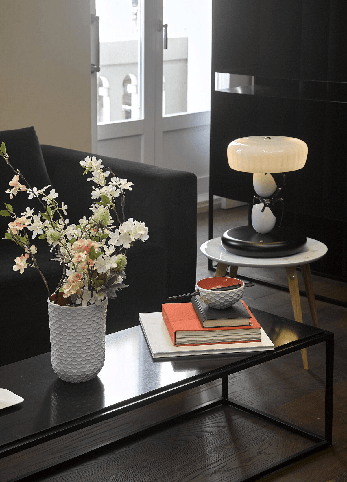 Lladró - Hairstyle (I/U) Table Lamp on a coffee table with flowers, books, and decorative bowl.
