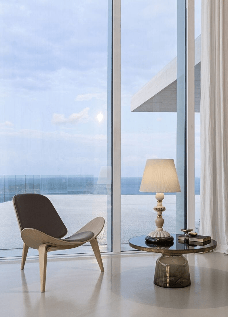 Lladró - Firefly Table Lamp - Pink and Gold on a modern table near a large window with ocean view.