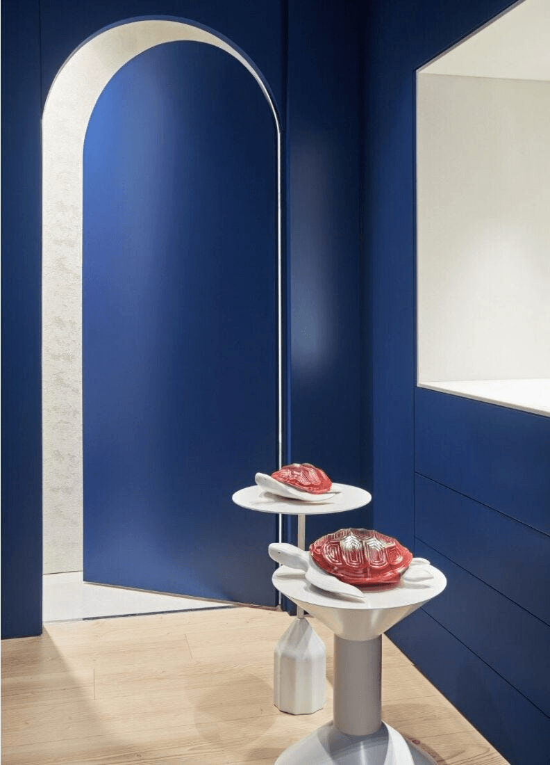 Lladró - Little Turtle Sculpture displayed on modern stands in a stylish blue interior, showcasing porcelain design.
