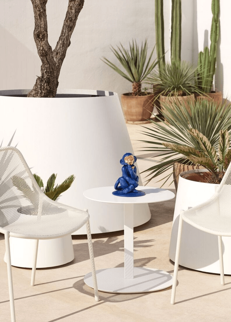 Lladró - Little monkey Sculpture - Blue-Gold - Limited Edition displayed on a white table in a tropical setting.