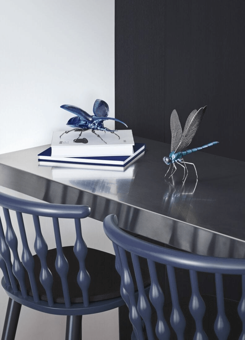 Lladró - Dragonfly Figurine displayed on books, showcasing intricate porcelain design and brass accents.