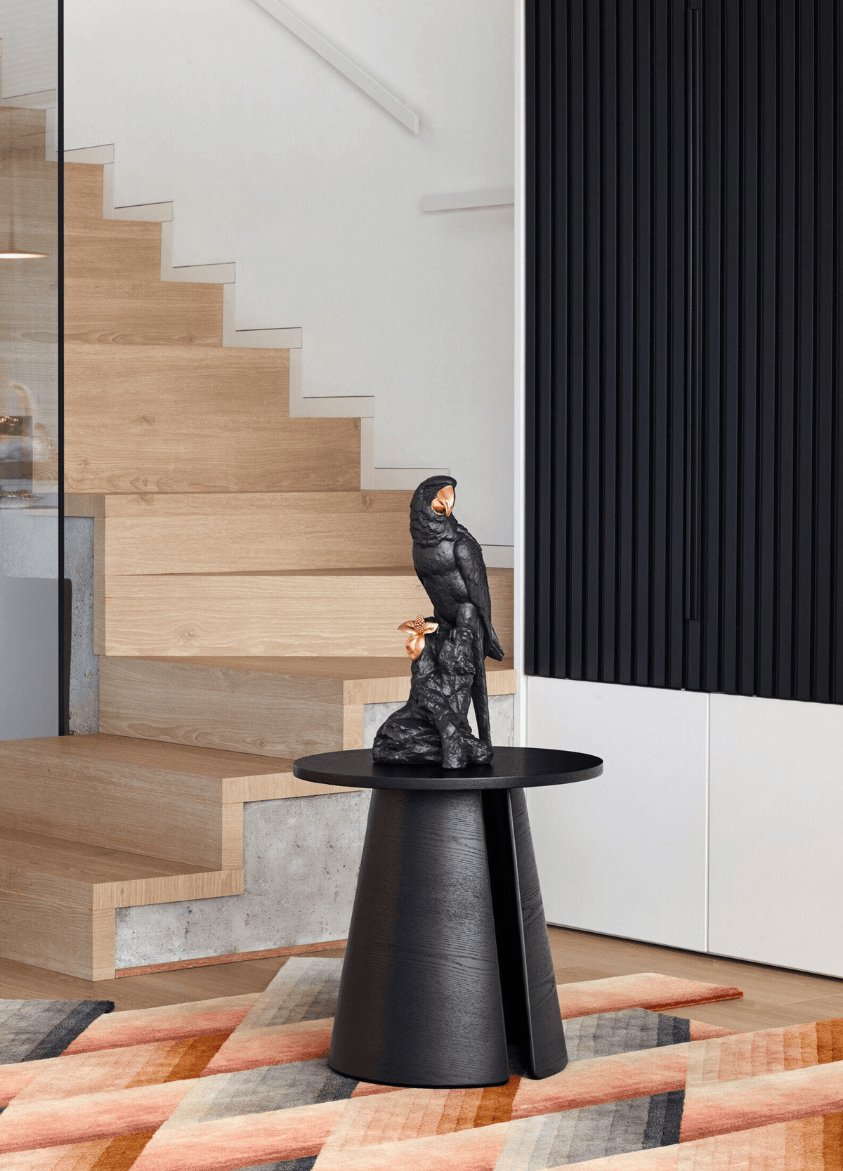 Lladró - Macaw Bird Sculpture - Black-Gold - Limited Edition placed on a stylish black table in a modern interior.