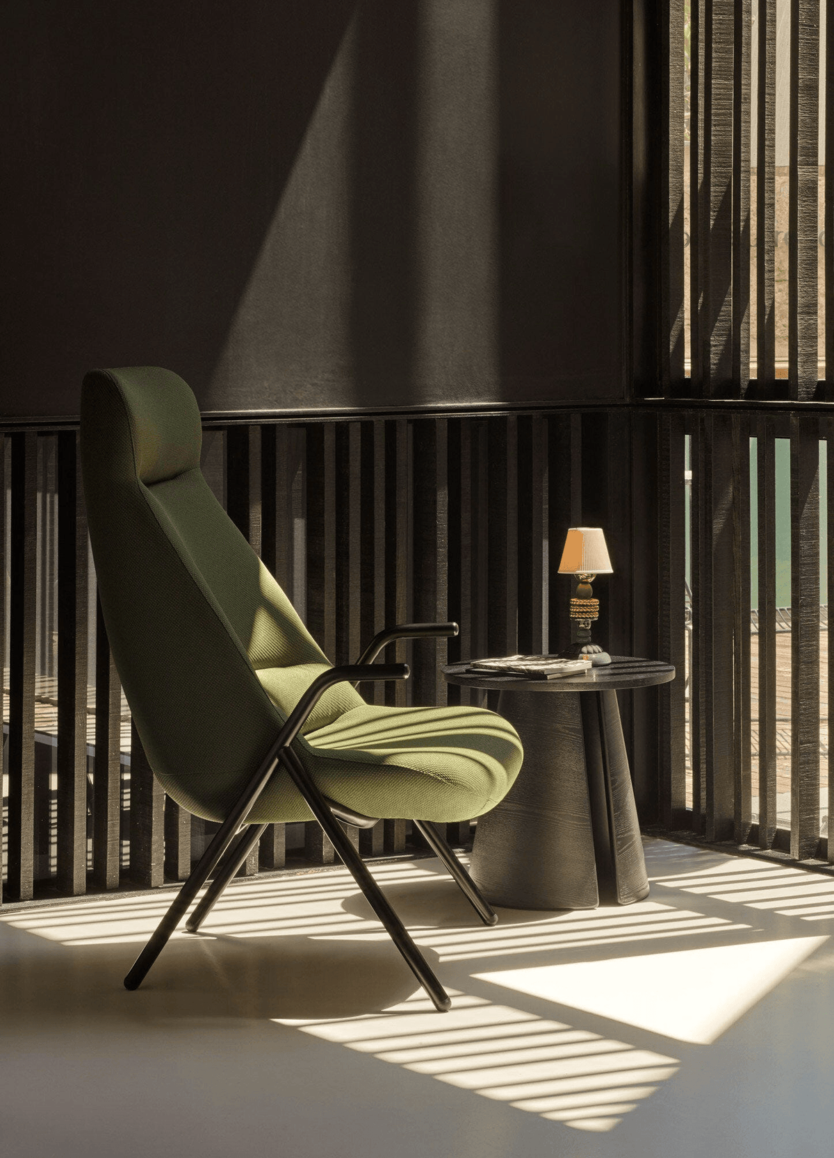 Lladró - Firefly cordless lamp by Olga Hanono in Lladro Porcelain on a table by a green chair.