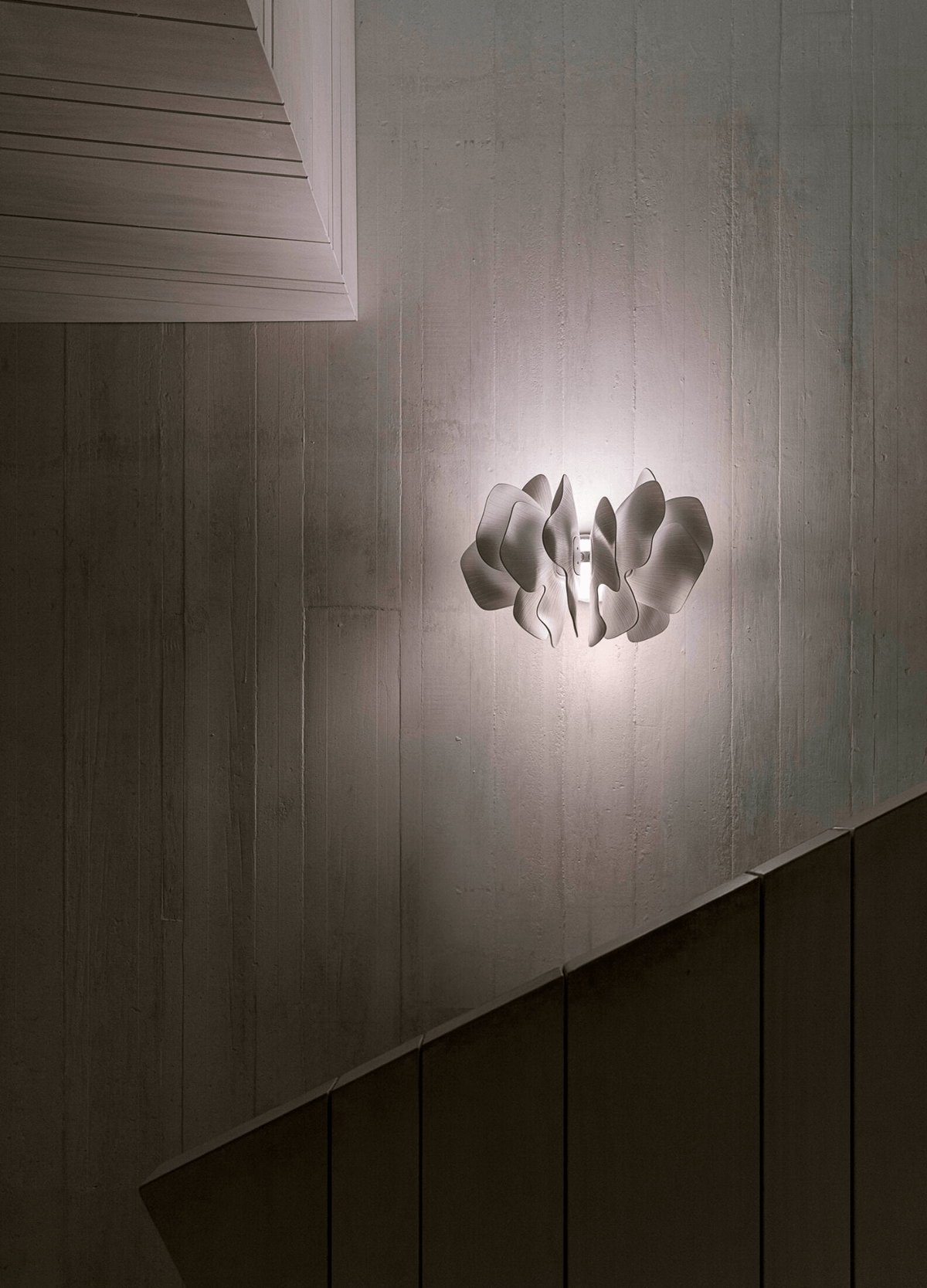 Lladró - Nightbloom Wall Sconce - White illuminating a textured wall, showcasing elegant porcelain design.