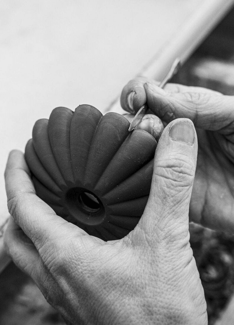 Craftsman shaping porcelain for the Lladró - Firefly Wall Sconce, showcasing artisan skill and attention to detail.