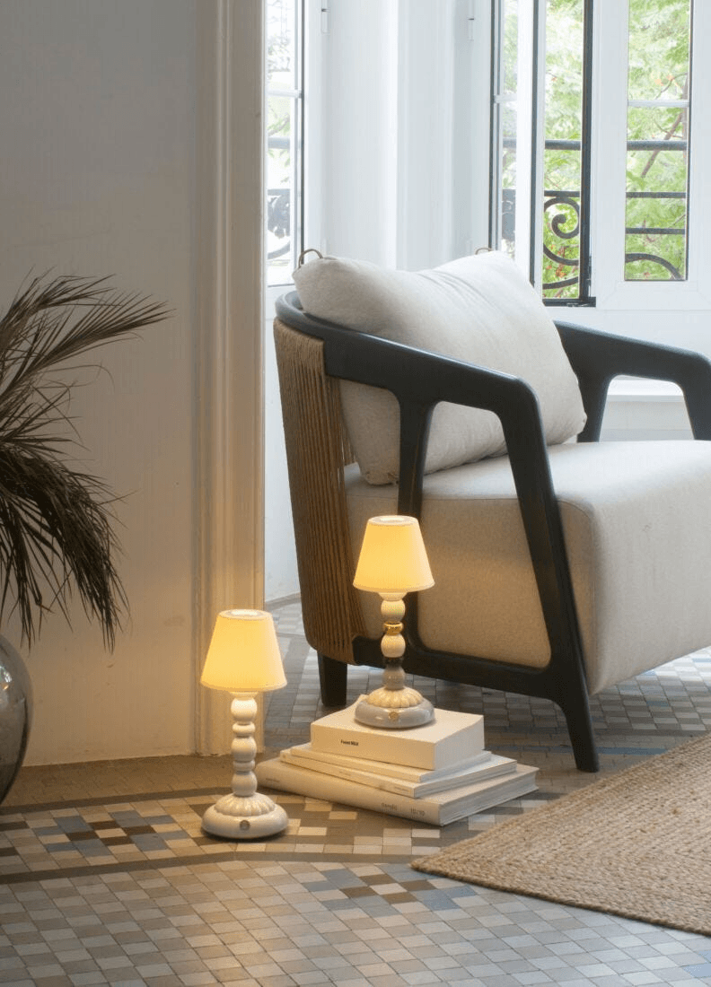 Lladró - Palm Firefly Table Lamp - White illuminating a stylish living room with a cozy armchair.
