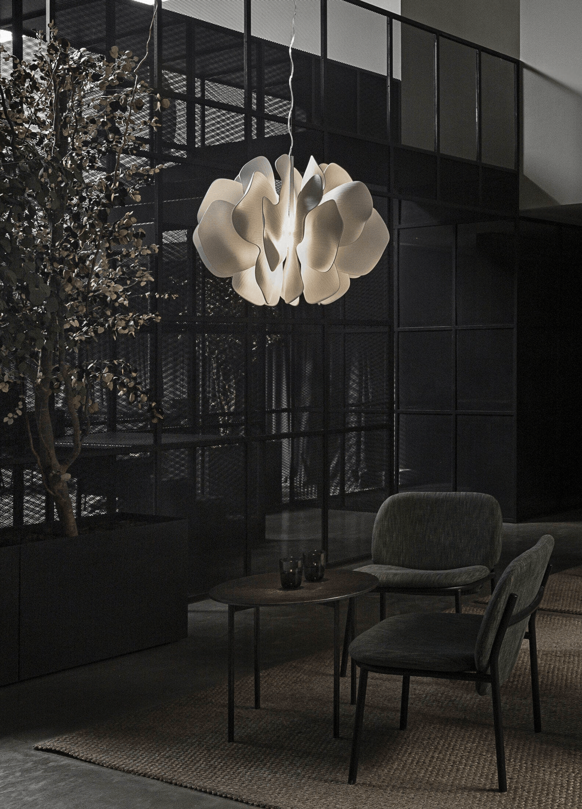 Lladró - Nightbloom Pendant Light - N40 - White shining above a modern seating area with greenery.