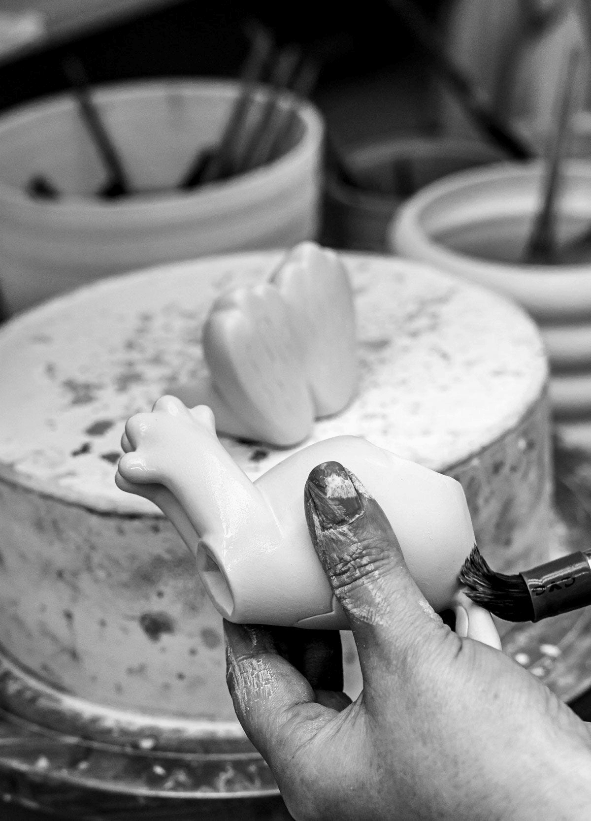 Lladró - Snoopy™ Flying Ace Figurine in porcelain being painted by an artisan's hand, showcasing the craftsmanship.