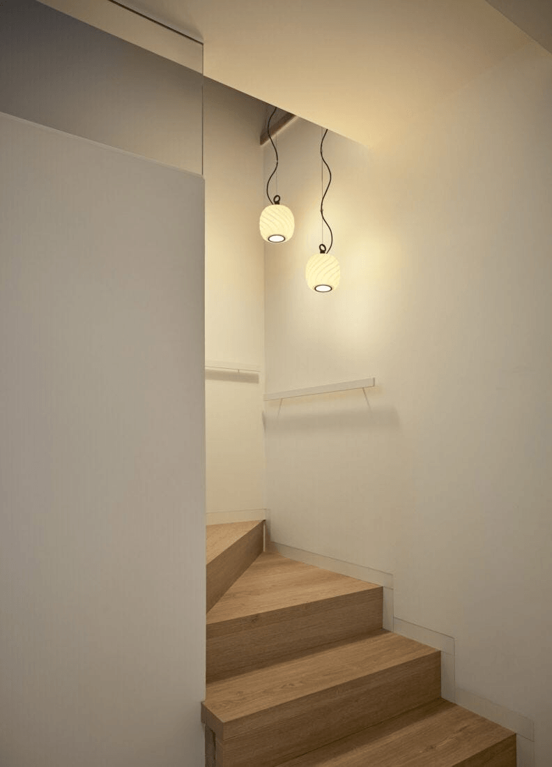 Lladró - Ice Cream Pendant Light illuminating a modern staircase with matte white porcelain and black iron accents.