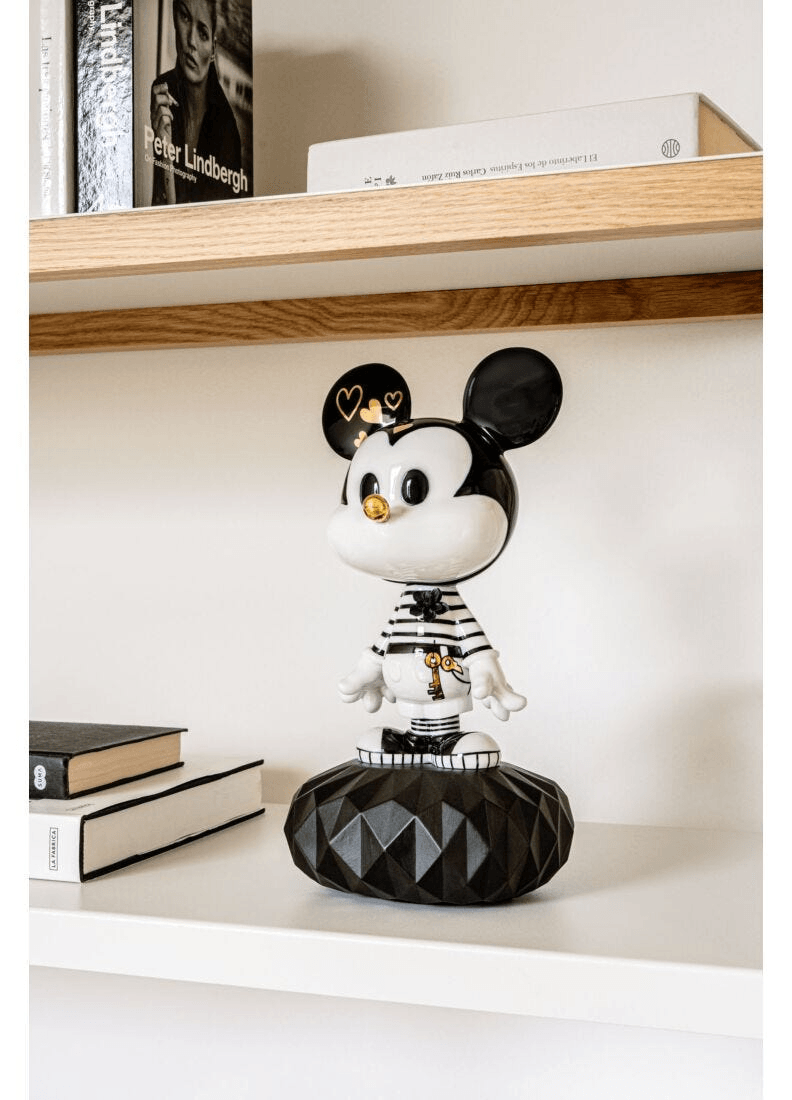 Lladró - Mickey in Black and White Sculpture displayed on a shelf with books, featuring intricate black and white designs.