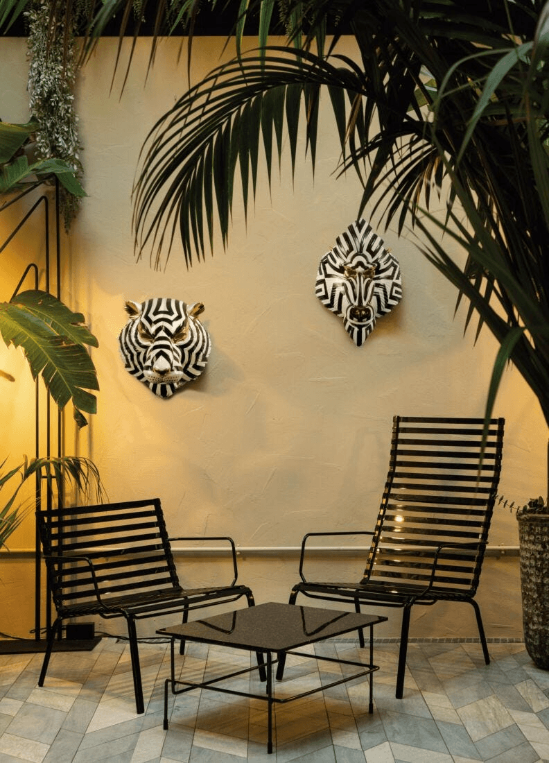 Lladró - Tiger Mask - Black and Gold displayed in a stylish living space with black furniture and lush plants.
