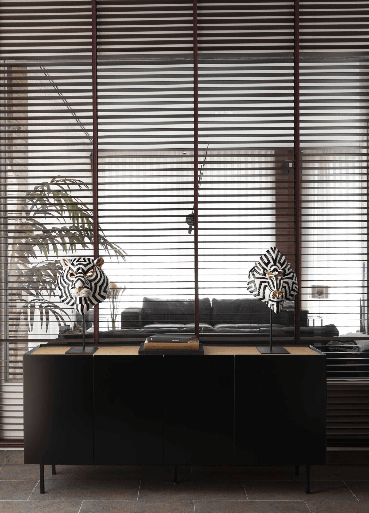 Lladró - Mandrill Mask - Black and Gold displayed on a modern black cabinet in a stylish interior.