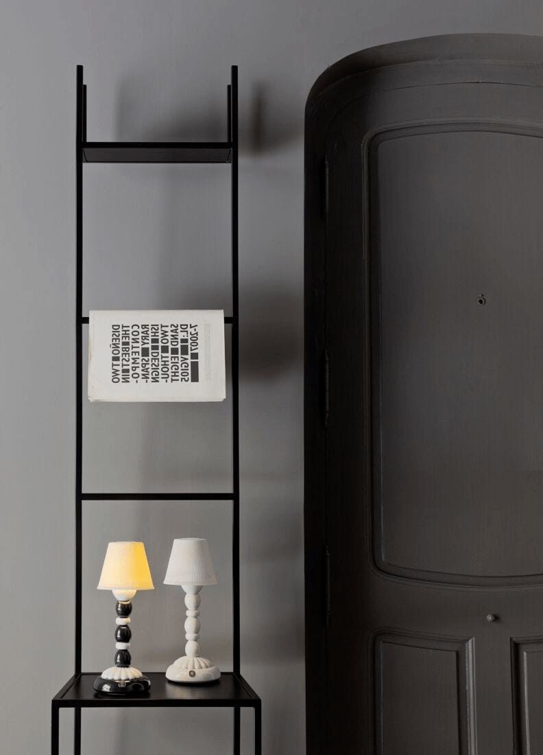 Lladró - Palm Firefly Table Lamp - Black and White displayed on a modern black shelf next to a door.