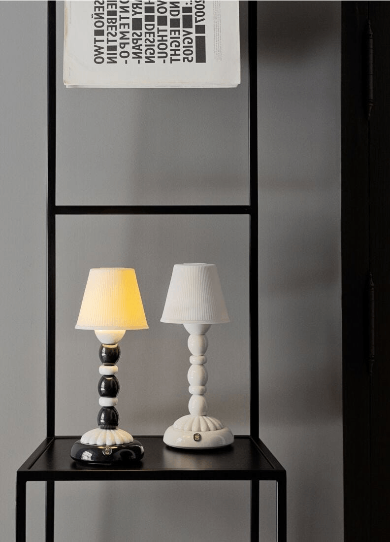 Lladró - Palm Firefly Table Lamp - Pale Blue displayed on a shelf with black and white lamps.
