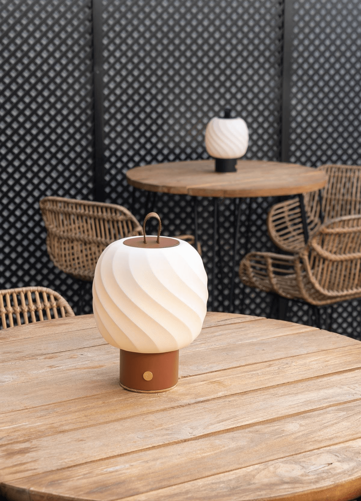 Lladró - Ice Cream Portable Lamp - Medium - Leather. White Lladro Porcelain lamp with a brown handle glowing on a wooden table.