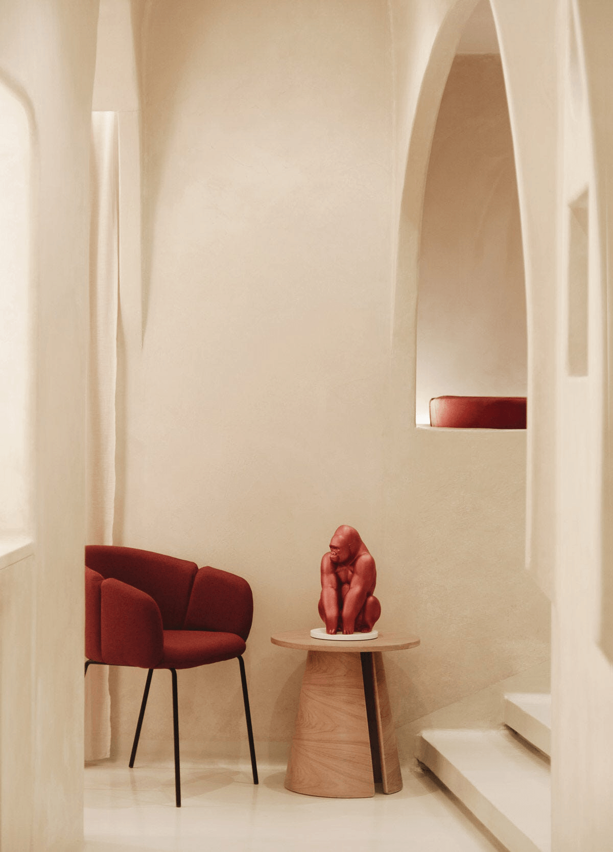 Lladró - Gorilla Sculpture - Metallic Red - Limited Edition displayed in a modern interior setting with a red chair.