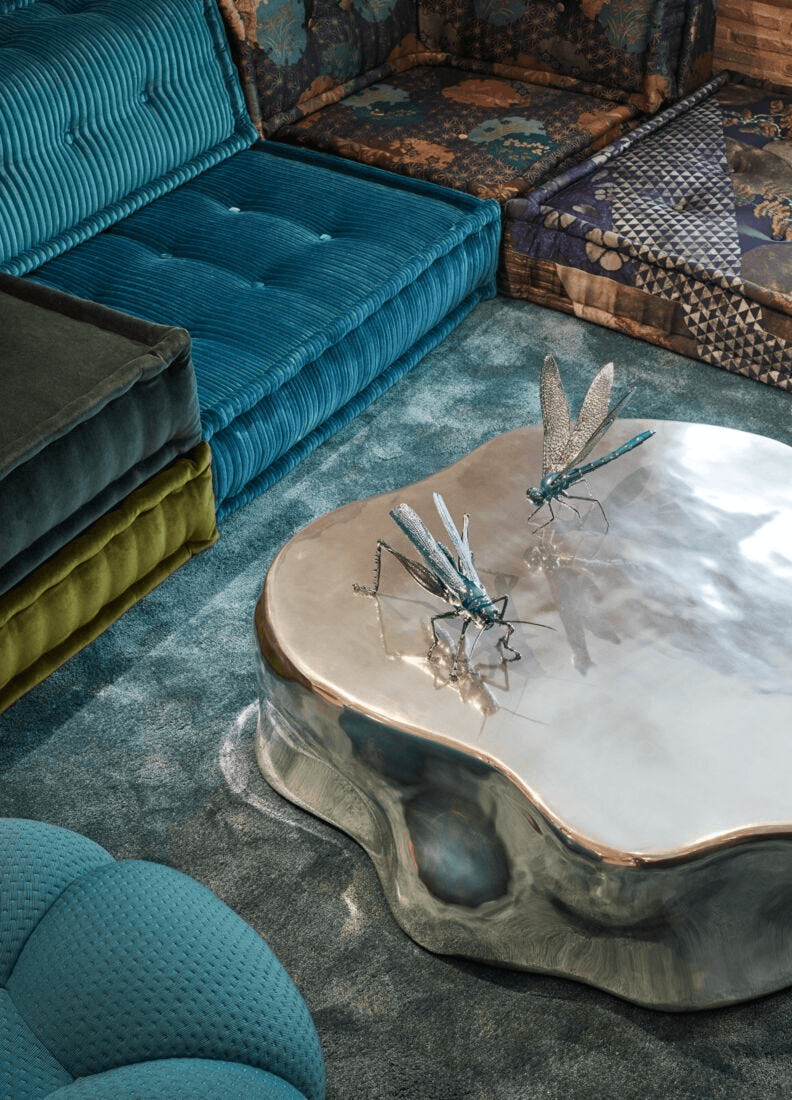 Lladró - Grasshopper Figurine displayed on a shiny table in a cozy living room setting with textured sofas.
