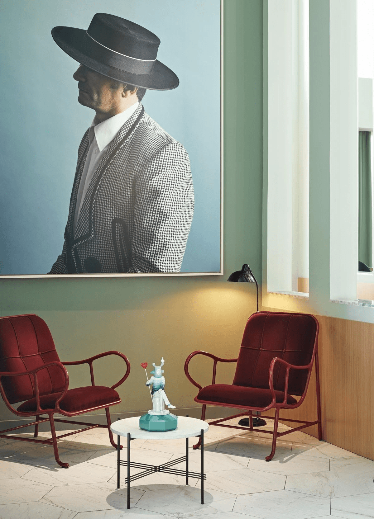 Lladró - The Lover I Sculpture displayed on a table between red chairs in a modern living space.