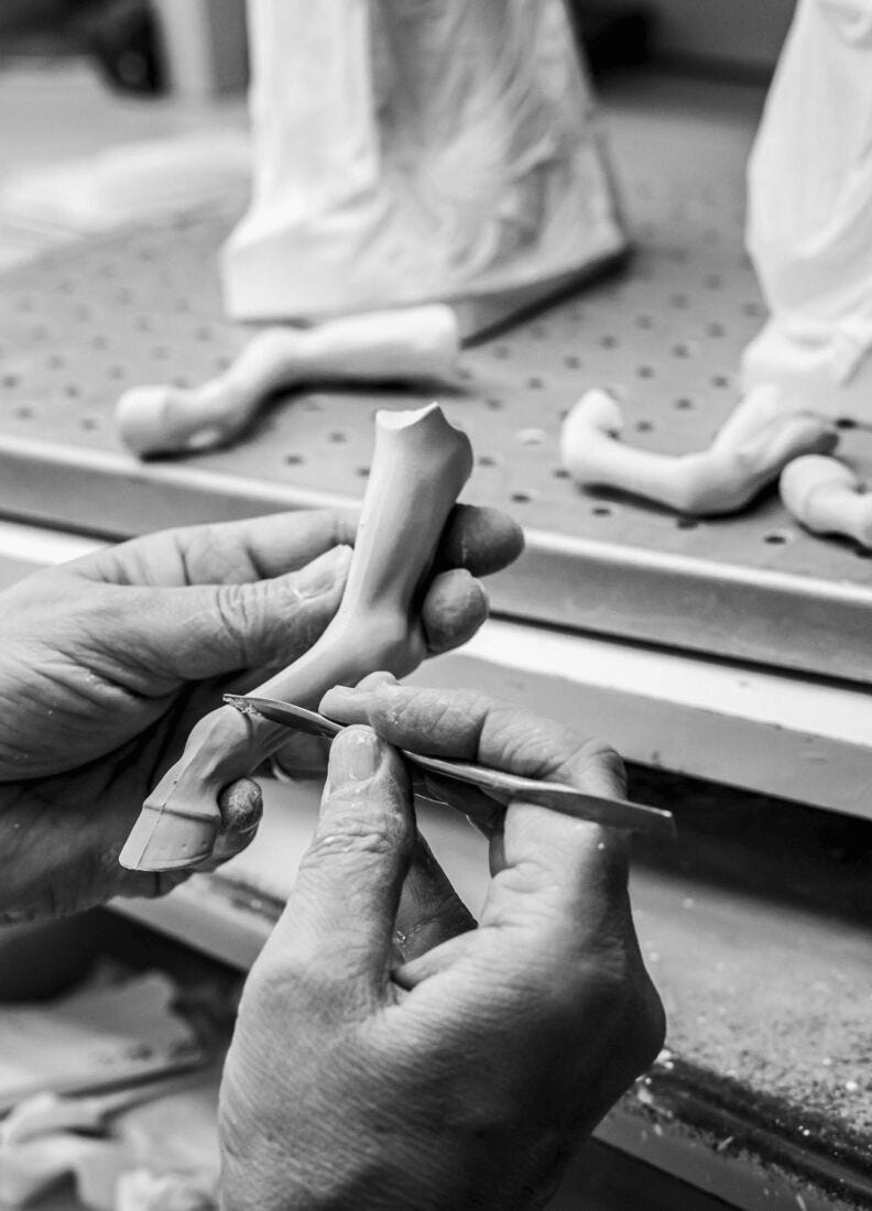 Craftsmanship in progress, hands shaping a Lladró porcelain figurine in a workshop.