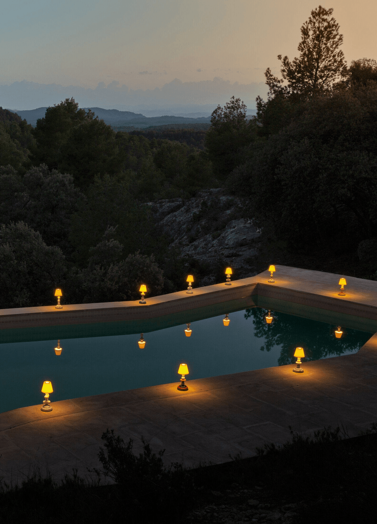Lladró - Sunflower Firefly Table Lamp - Blue in Lladro Porcelain glowing by a pool at dusk.