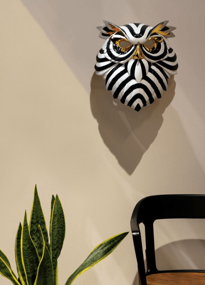 Lladró - Owl Mask - Black and Gold displayed on a wall, featuring glossy porcelain and golden accents.