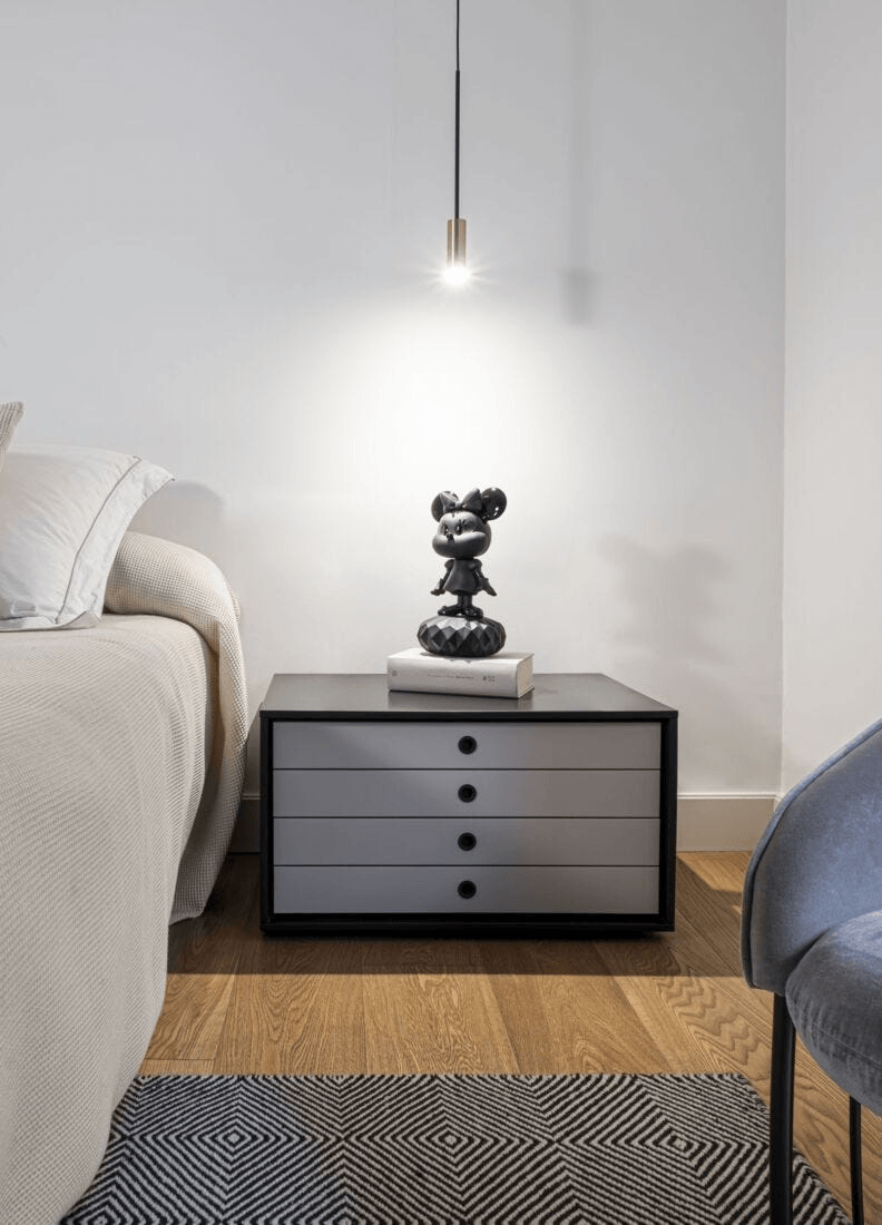Lladró - Minnie Total Black Sculpture displayed on a bedside table next to a modern lamp and bedding.