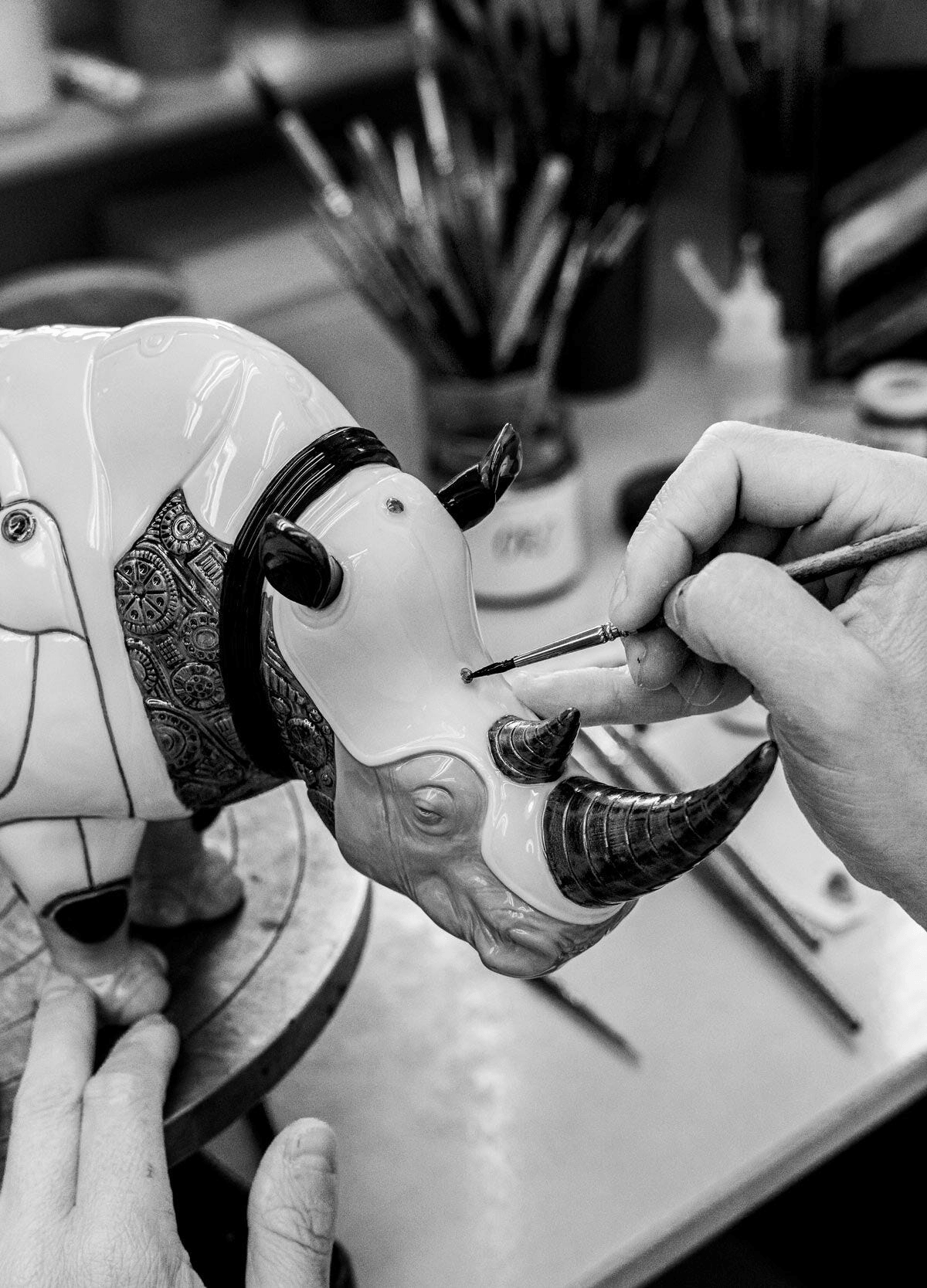 Artist painting the Lladró - Rhino Cyborg Sculpture, showcasing intricate porcelain details.