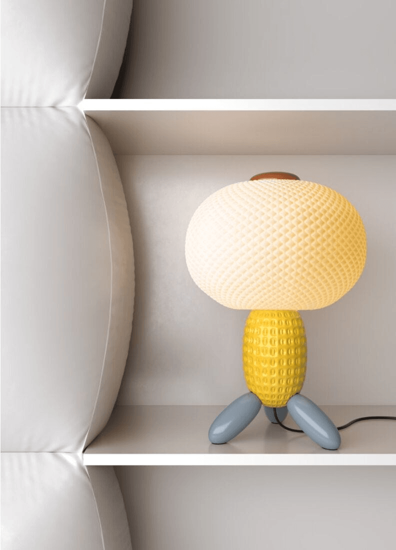 Porcelain Lladro design: Lladró - Soft Blown Table lamp - Yellow illuminating a white shelf.