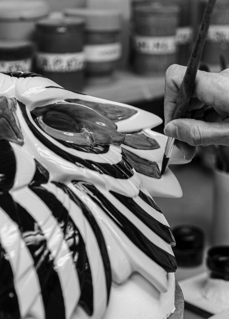 Artisan painting the Lladró - Owl Mask - Black and Gold with glossy porcelain details and bold black design.