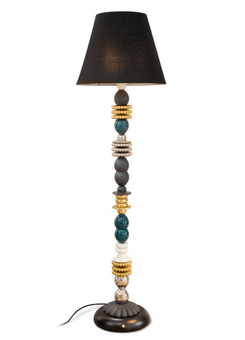 Decorative table lamp with beaded base and black shade on a white background