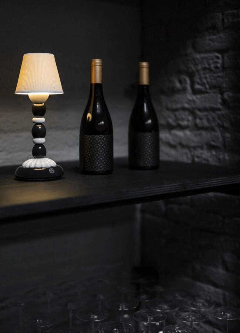 Lladró - Palm Firefly Table Lamp - Black and White displayed beside wine bottles in a stylish setting.
