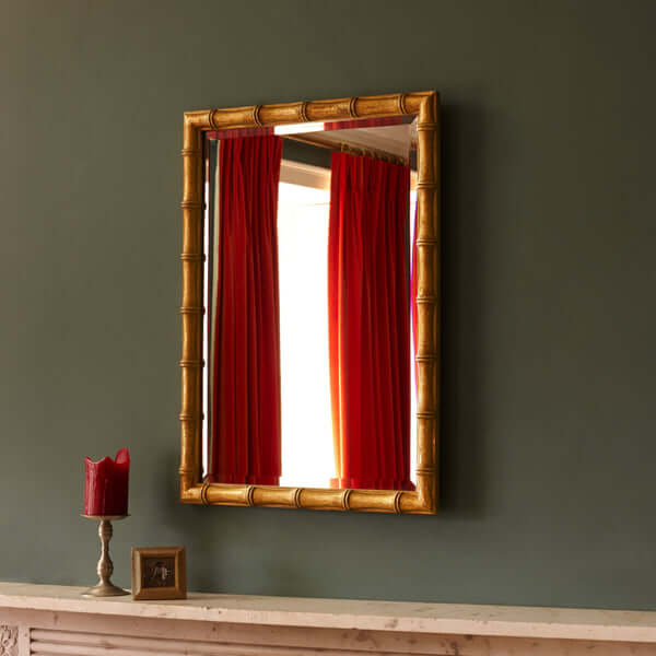 Pooky - Baloo Mirror - Gold Finish displayed on a green wall with red curtains and decorative items.
