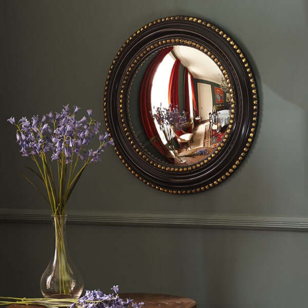 Pooky - Marilyn Mirror reflecting a stylish room and flowers, showcasing classic convex design on a dark wall.