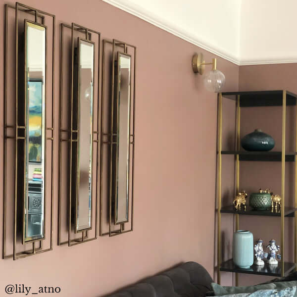 Pooky - Rectangular Necklace Link Mirror - Antique Gold displayed in a living room with three mirrors against a pink wall.