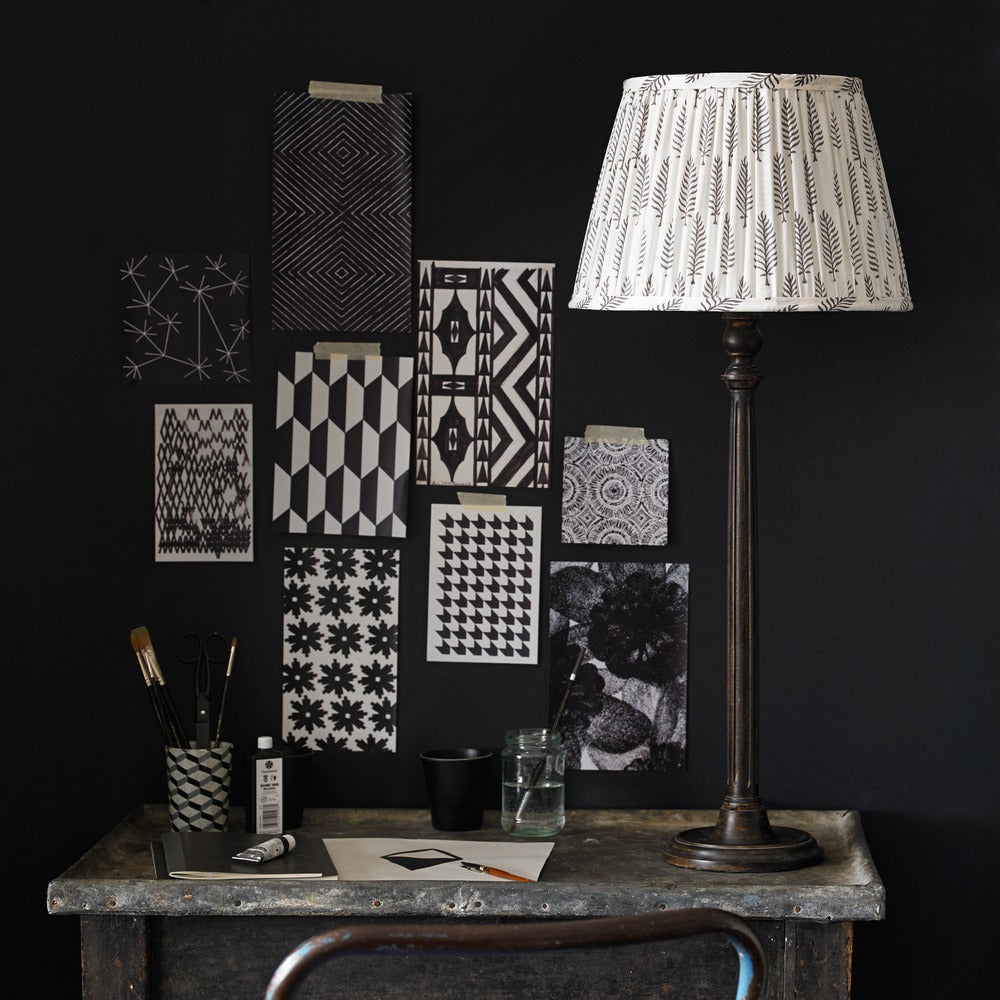 Pooky - Luty Table Lamp Base - Mahogany with patterned shade on an artist workspace desk.