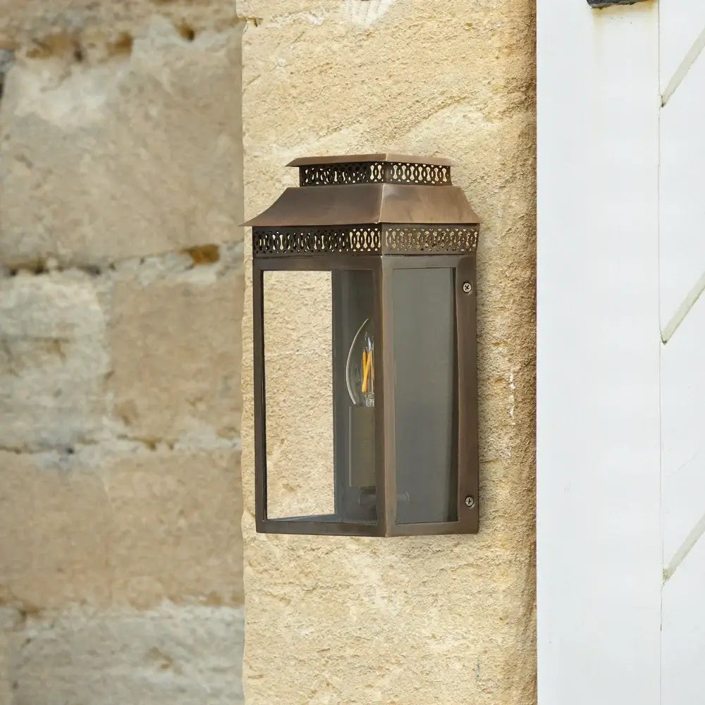 Pooky Hastings Exterior IP44 Wall Light in Bronze illuminating a stone wall.