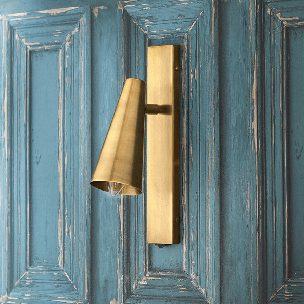 Pooky - Victor Wall Light - Antique Brass mounted on a blue wooden wall.