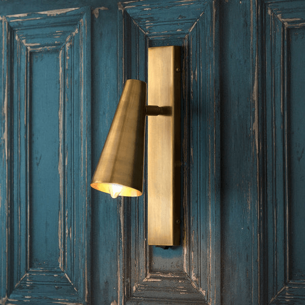 Pooky - Victor Wall Light - Antique Brass mounted on a rustic blue wall, showcasing its elegant design and directed beam.