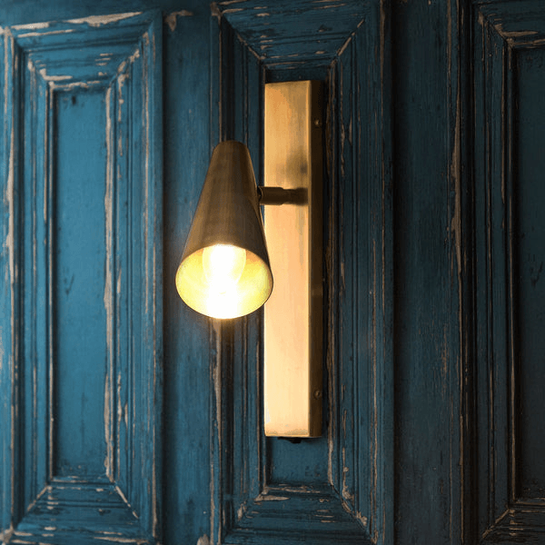 Pooky - Victor Wall Light - Antique Brass mounted on a blue wooden wall, providing focused elegant lighting.