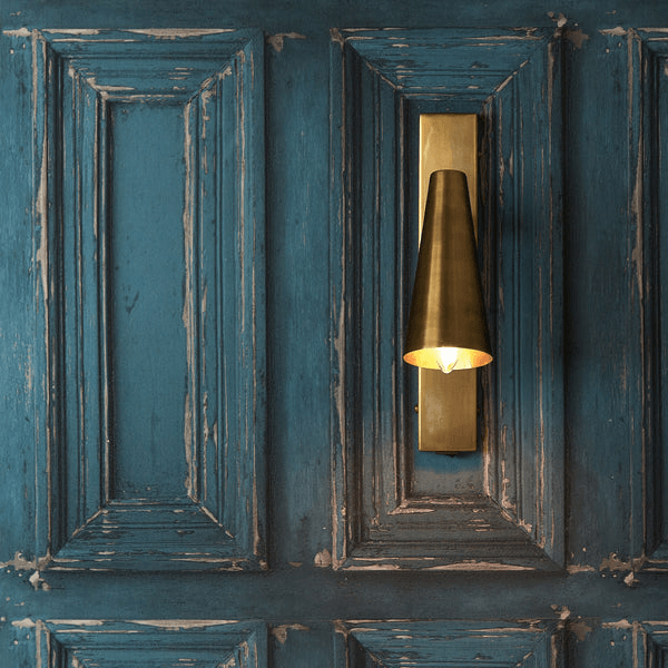 Pooky - Victor Wall Light - Antique Brass mounted on a blue paneled wall, showcasing its elegant design and warm light.