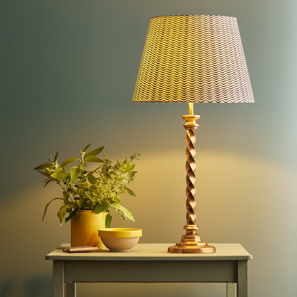 Pooky - Cavendish Table Lamp Base - Aged Brass featuring a twisted design, paired with a patterned shade on a side table.