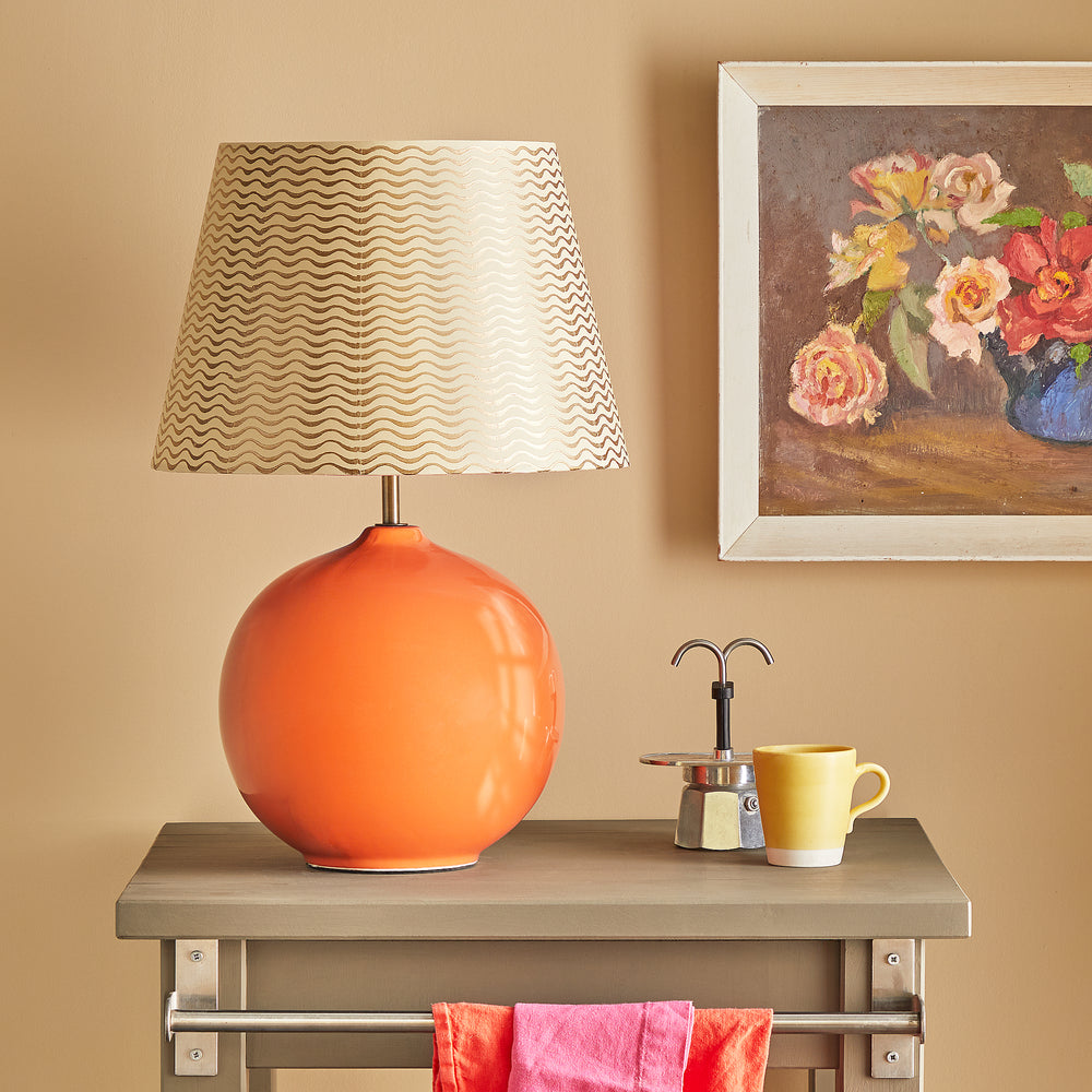 Pooky - Olly Table Lamp Base - Orange with a patterned shade on a grey side table.