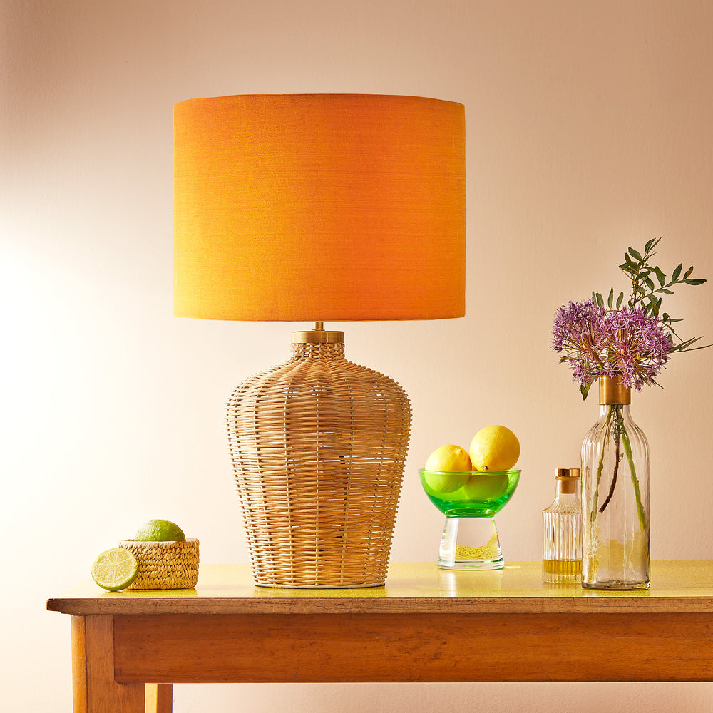 Pooky - Regular Rattle Table Lamp Base - Natural Cane paired with an orange lampshade, styled on a wooden table.